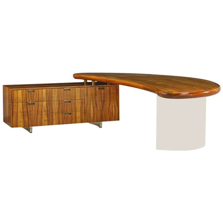 An outstanding custom wing desk rendered in Koa wood and acrylic with patinated brass hardware, it’s curved form floats on a Lucite base. Giving levity to its appearance, the other end of the desk rests upon the adjacent cabinet, fit with drawers