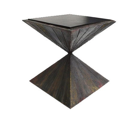 A rare sculpted steel side table with a slate top, comprised of two pyramidal forms joined at the center. The metal is enameled in long triangular sections in subtle blue, red and yellow. The surface is enlivened with a regular pattern of rugged