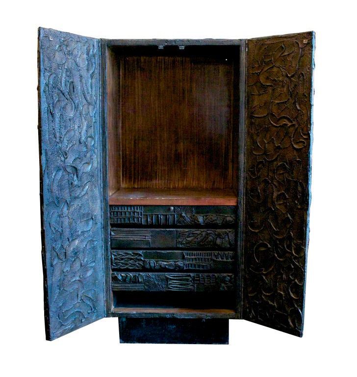 A Sculpted Bronze tall cabinet by Paul Evans. USA, Circa 1969. A tall two-door cabinet on steel-shingled recessed base with four interiror drawers and adjustable shelves. This cabinet is an outstanding example of Paul Evans sculpted bronze technique