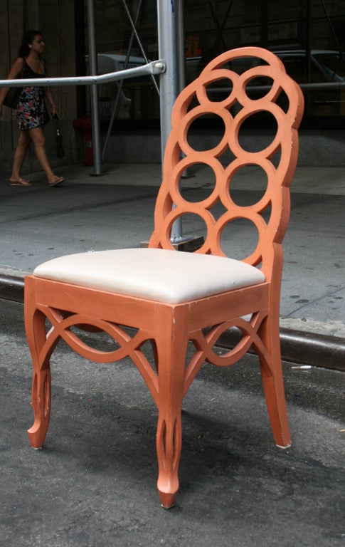 A set of four of high back salon chairs with a coral lacquer finish upholstered in cream leather.  Chairbacks in solid wood with a carved loop pattern. Frances Ellkins got her start renovating luxury estates in Northern California. These chairs