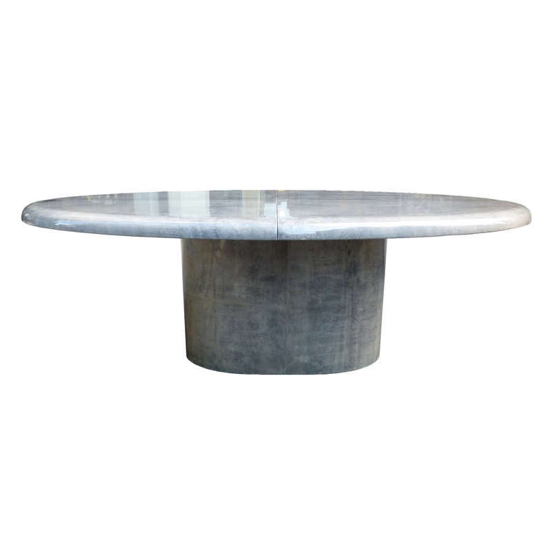An oval grey lacquered goat skin dining table by Aldo Tura. The table with 3″ bull nose edge, double pedestal with one leaf. The finish in excellent condition, beautifully matched skins dyed grey. The skins cut and matched foursquare on the top of