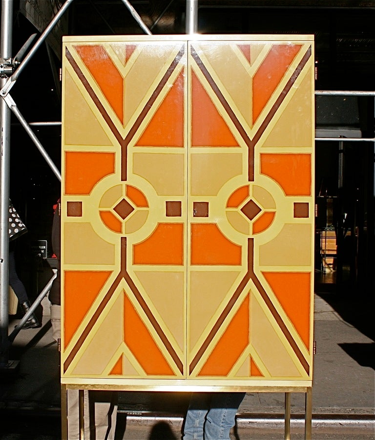 This rare documented Parzinger Originals bar cabinet is hand-painted and lacquered with a unique design. The colors in soft celery green, apricot, coco brown and cornsilk wrap the cabinet. The tall cabinet is mounted on a bronze base and features a