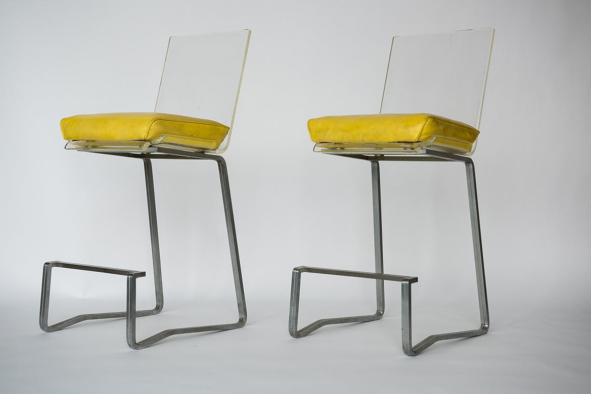 This fantastic pair of bar stools by Erwine and Estelle Laverne, circa 1960, are made of solid brushed steel legs with original Lucite and back rests with original yellow vinyl upholstery. The vinyl and Lucite’s age appropriate patina adds a
