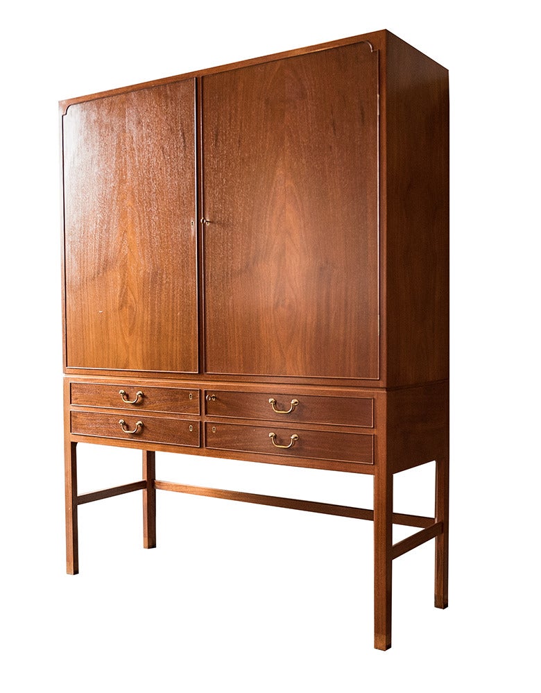 This beautiful solid mahogany cabinet by Ole Wanscher features an original oiled finish. Two keyed doors over four keyed drawers offer incredible storage, with each side fitted with three adjustable shelves. All hardware is original brass. The piece