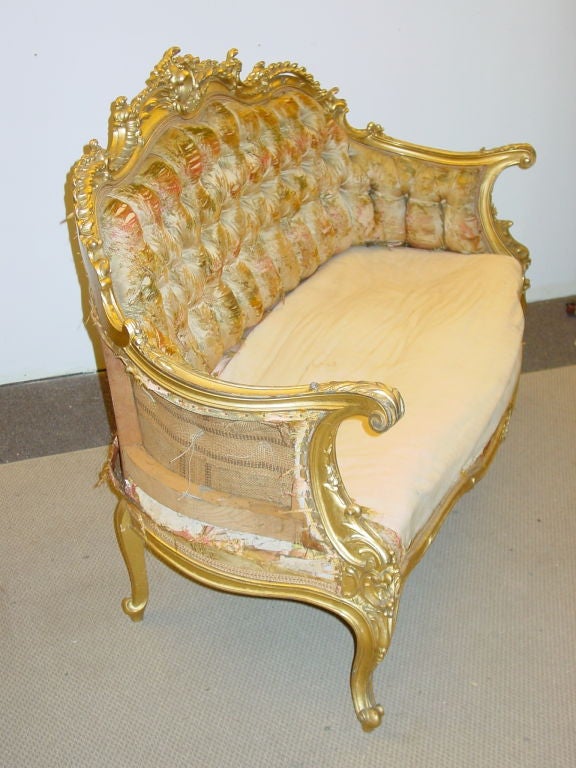 the arched padded back out scrolling arms and serpentine padded seat in a conforming elaborately pierce carved foliate scrolling frame on cabriole legs with scrolling feet