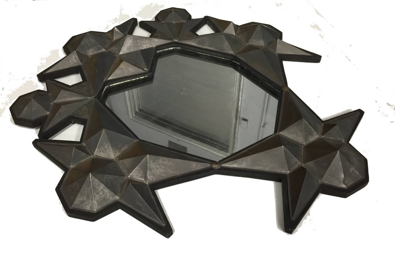 Wooden frame mirror with handmade pyramid shaped distress metal pieces positioned to create a three dimensional sculpture.

Made in Mexico.