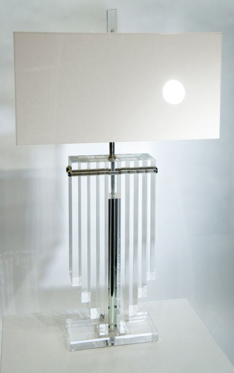 Spectacular deco-disco design from the 1970s. A massive table lamp, made of nine vertical piers of shimmering clear Acrylic Lucite, held together with chromed steel bolts. The central cylinder contains the newly rewired electrical components.