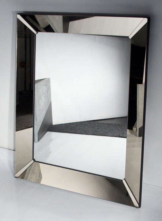 Clear mirror in a five-inch frame of angled bronze-mirror panels.  Corner brackets also in bronze mirror.  Mounted on a framework of 3/4