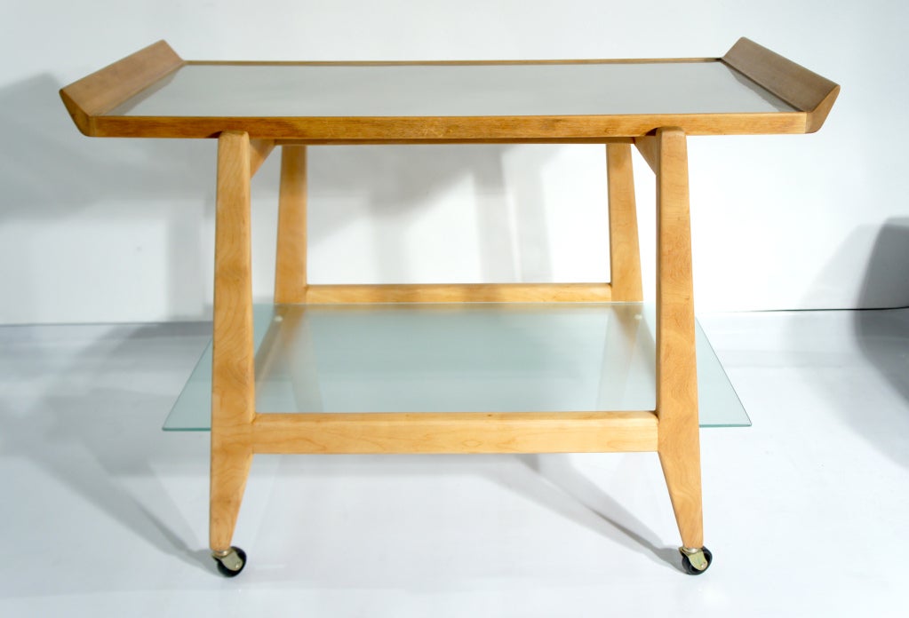 Rolling bar cart by Jens Risom. Birch framework, textured-glass lower shelf. Gray laminate top shelf doubles as a stylish serving tray.