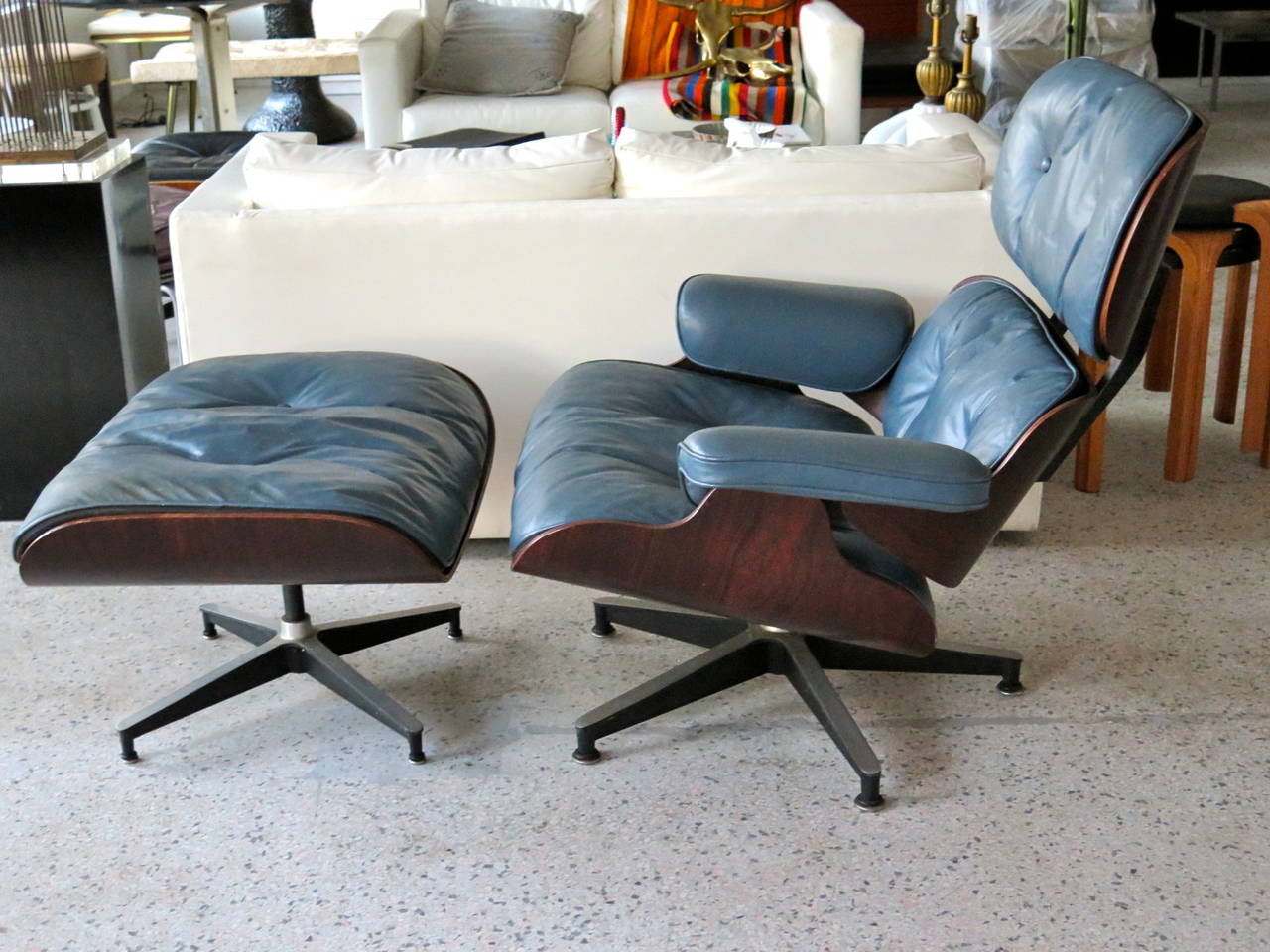 A rare Charles Eames for Herman Miller lounge chair and ottoman. Blue leather, rosewood shell, four prong base.