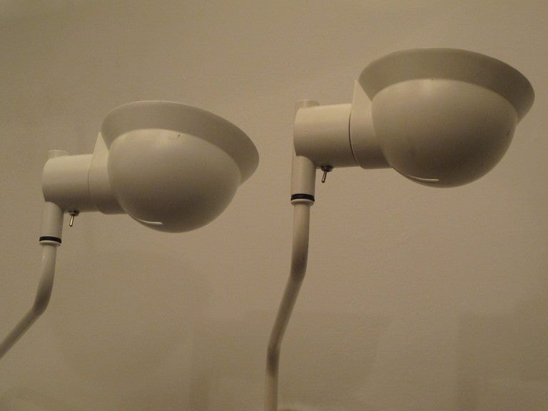 An interesting pair of Ron Rezek reading lamps/wall lights. Swiveling head allows light to be directed in different ways.  One is in original, unused packaging. One lamp is slightly more cream colored than the other.