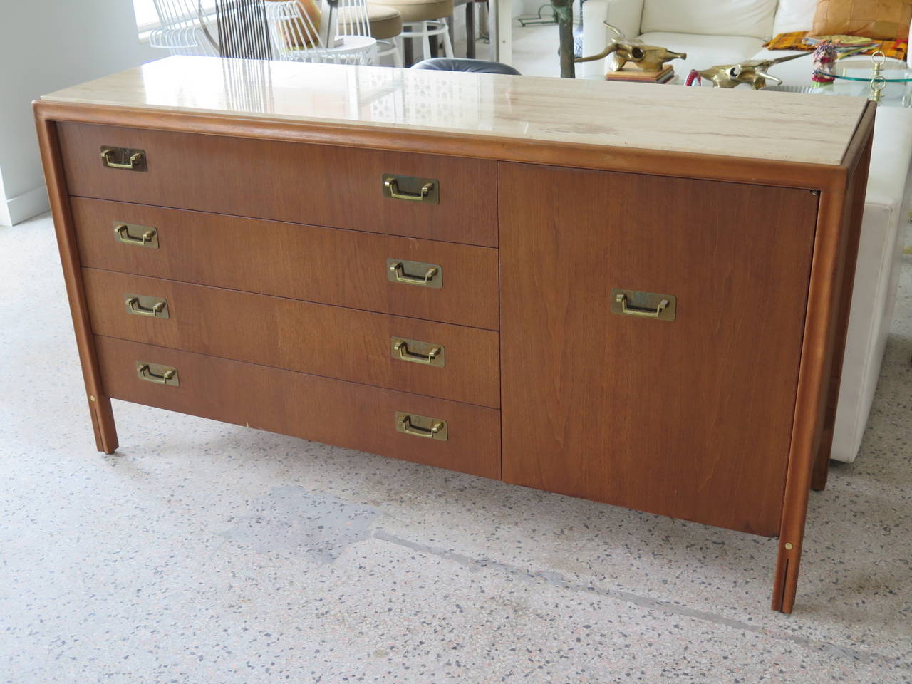 An unusual credenza by Gerry Zanck for Gregori I walnut with travertine top. Interesting brass handles and scalloped legs with brass detailing. Four drawers on one side and four smaller drawers with a door front. Finished on the back-so could easily