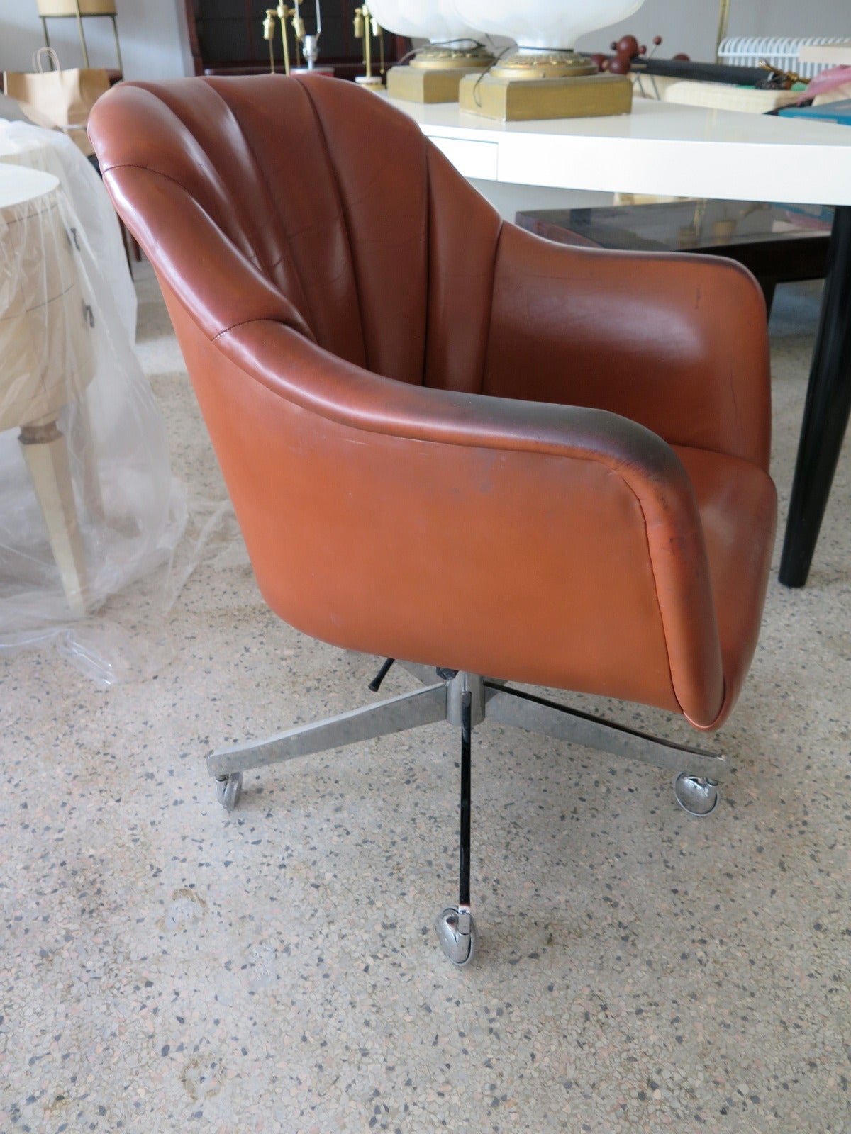 An office or desk chair by Ward Bennett for Brickell. Original brown leather, swivel and tilt. Stainless base with casters.