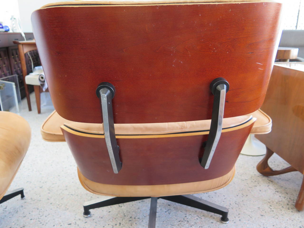 A Classic Charles Eames 670 lounge chair with two (2) ottomans. Original baseball glove patinated leather soft and supple. Walnut veneer. Signed Herman Miller and dated 1996.