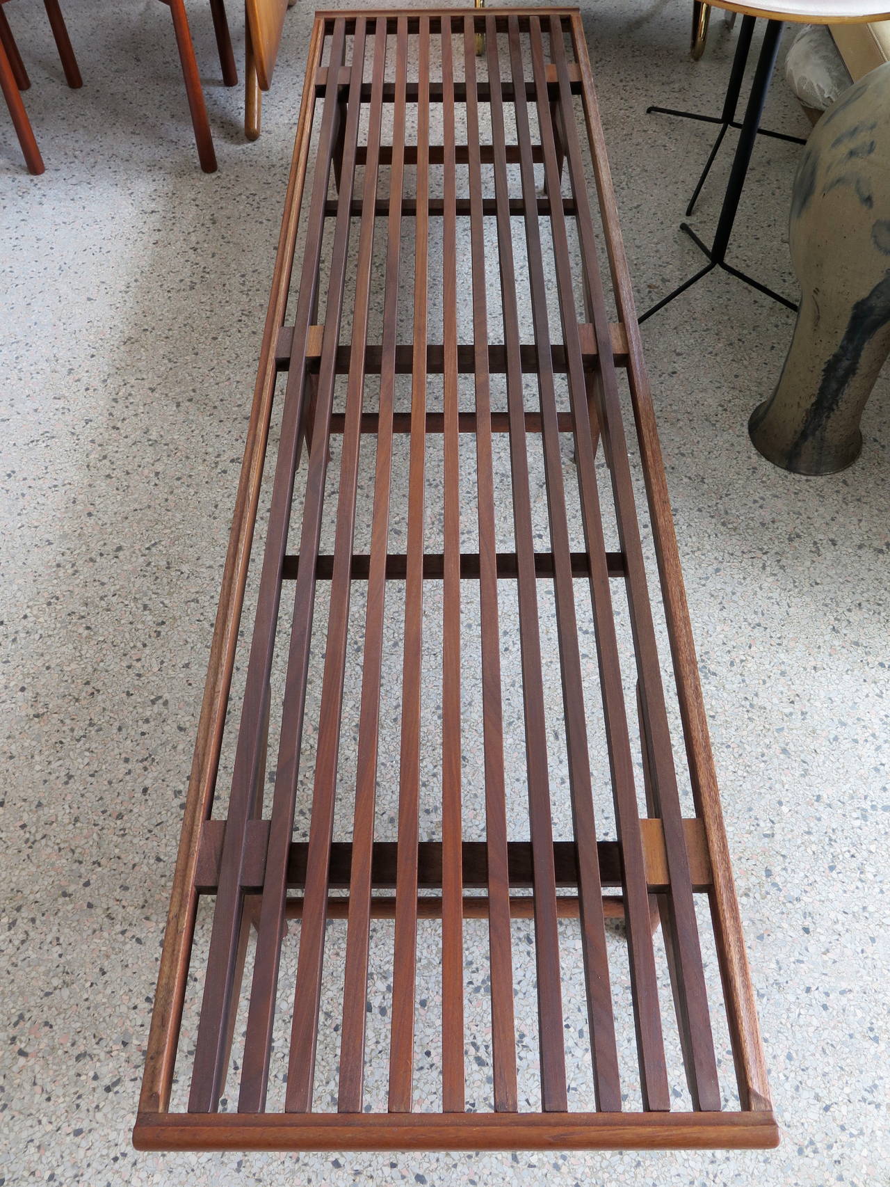 A quality, well-made Danish modern slat bench in teakwood. Comes with four cushions.