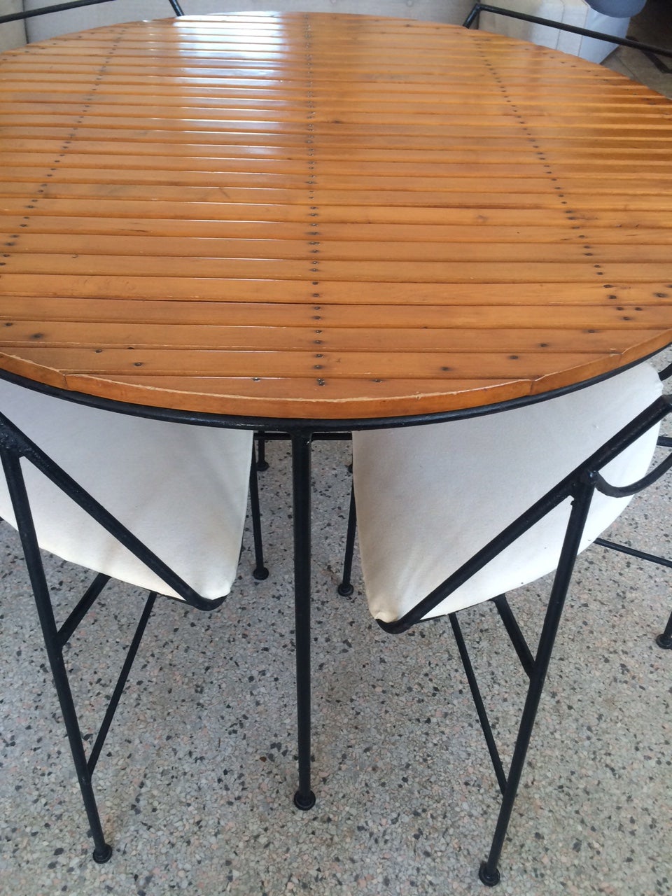 An Arthur Umanoff dining set with table and four pie shaped chairs fitted underneath. Wrought iron construction, heavy and well made. Table has slats on top with exposed nail heads a la Sornay. Nice patina, probably restored at some point. Foot