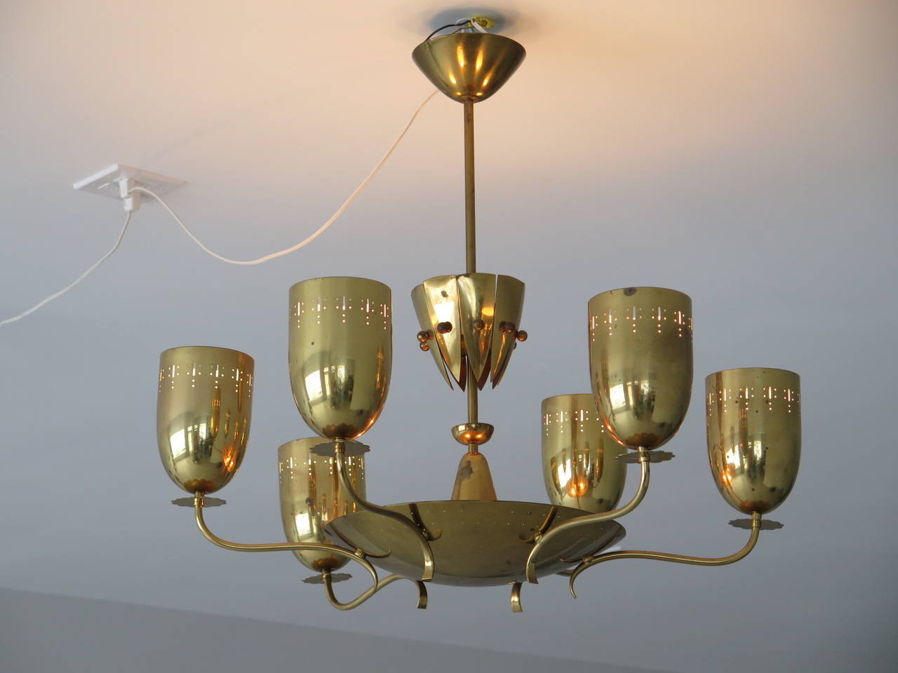 A large and highly stylized German chandelier from the 1950s, in polished brass. Six arms with decorations and lighted central dish with perforations.