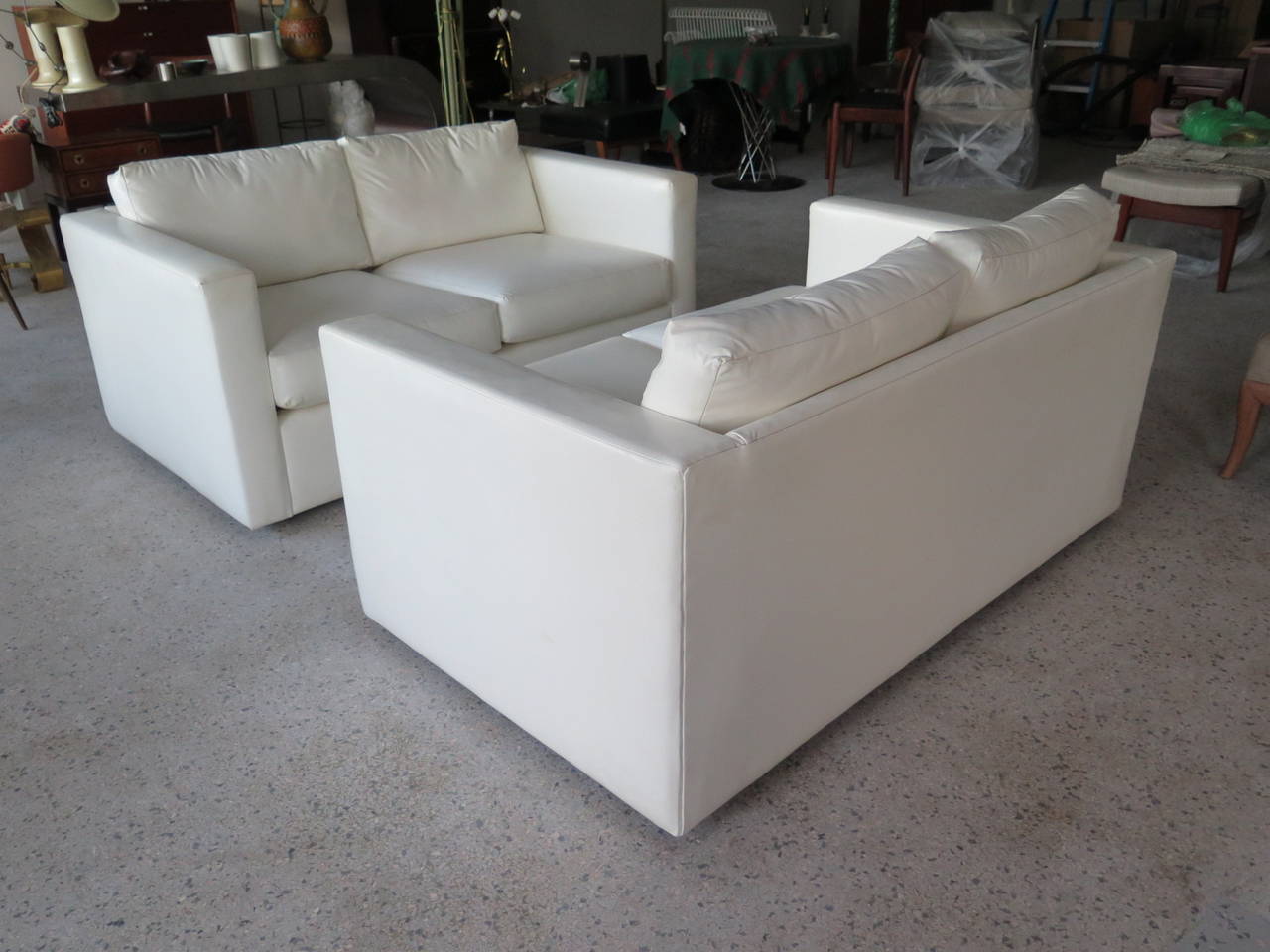 A Classic pair of signed Milo Baughman for Thayer Coggin settees, circa 1970s.
Original white vinyl upholstery, simple boxy, rectangular shapes, with small plinth legs for a slightly raised, floating effect. Loose cushions and pillows.
