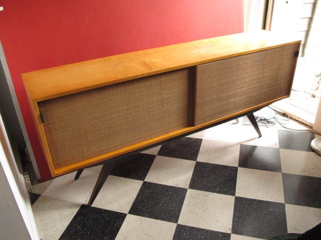 A rare credenza by Florence Knoll for Knoll ca' 1940's. Grass cloth sliding doors, long tapering legs, adjustable shelves inside, leather tab handles.
