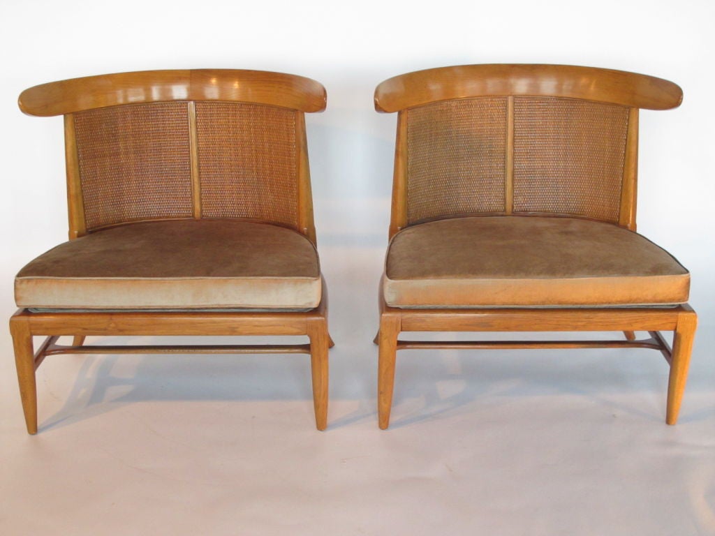 A pair of elegant Tomlinson lounge chairs. Caned back with loose seat cushion. Sculptural, wrap around back support.