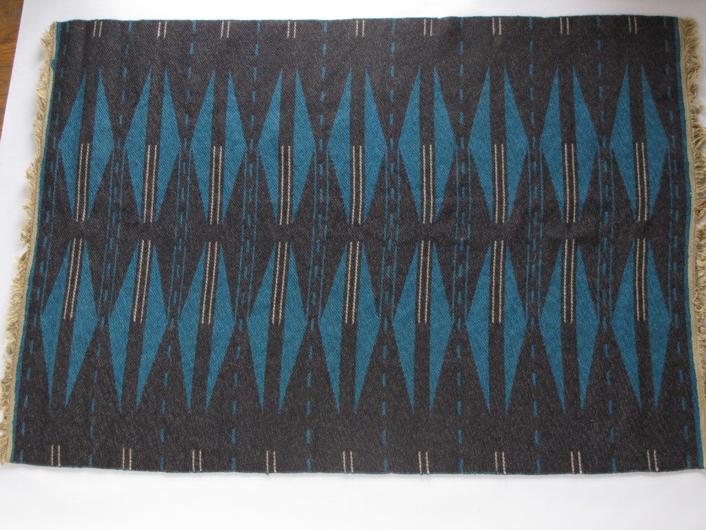 A modernist, handwoven Swedish carpet in a simplified, geometric pattern.