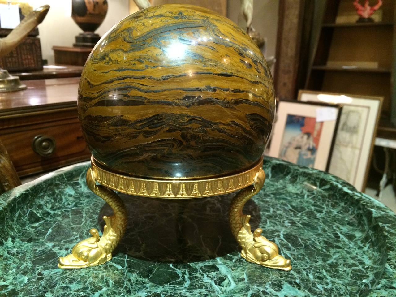 A handsome marble agate-like orb on a Italian neoclassical style gilt bronze tripod stand with three dolphin supports.