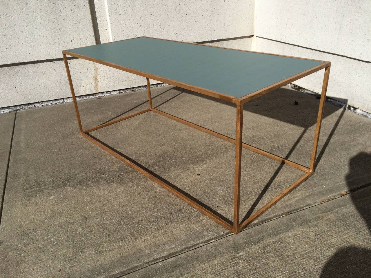 French modern gilt iron coffee table of geometric form with glass mirror top.