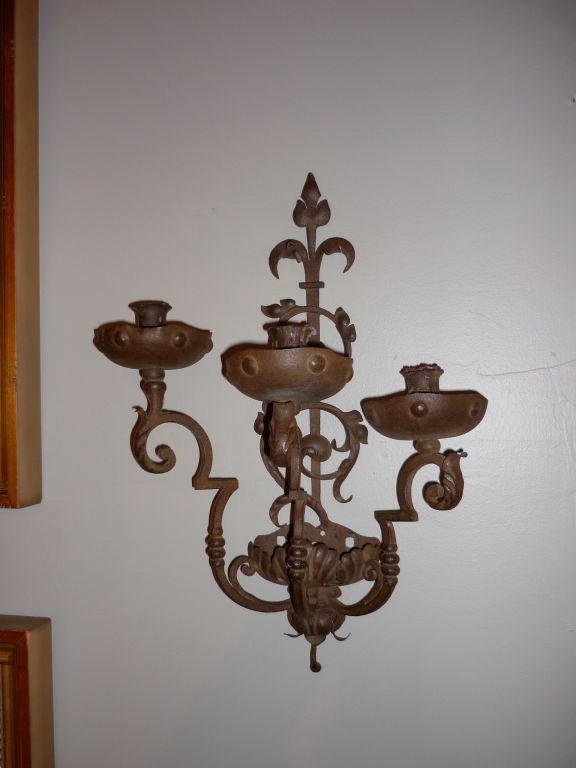Pair of Italian Baroque style wrought iron three-light sconces. The three arms showing exquisite hand wrought iron work. These are in their original state, meant for candles, but can be wired for electricity. They will work well in a Mission or
