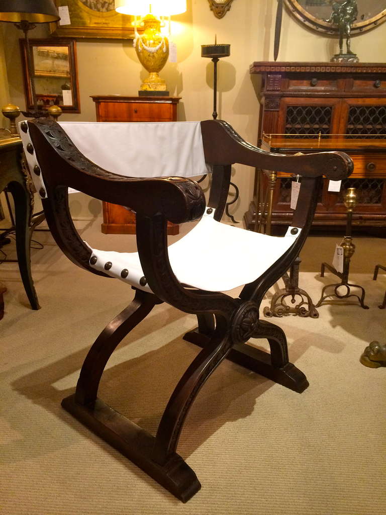 Pair of Italian Renaissance style walnut curule chairs in the Dantesca style with carved relief decoration throughout. These folding chairs are similar to Savonarola chairs but solid rather than slated, named for the Italian Renaissance poet Dante