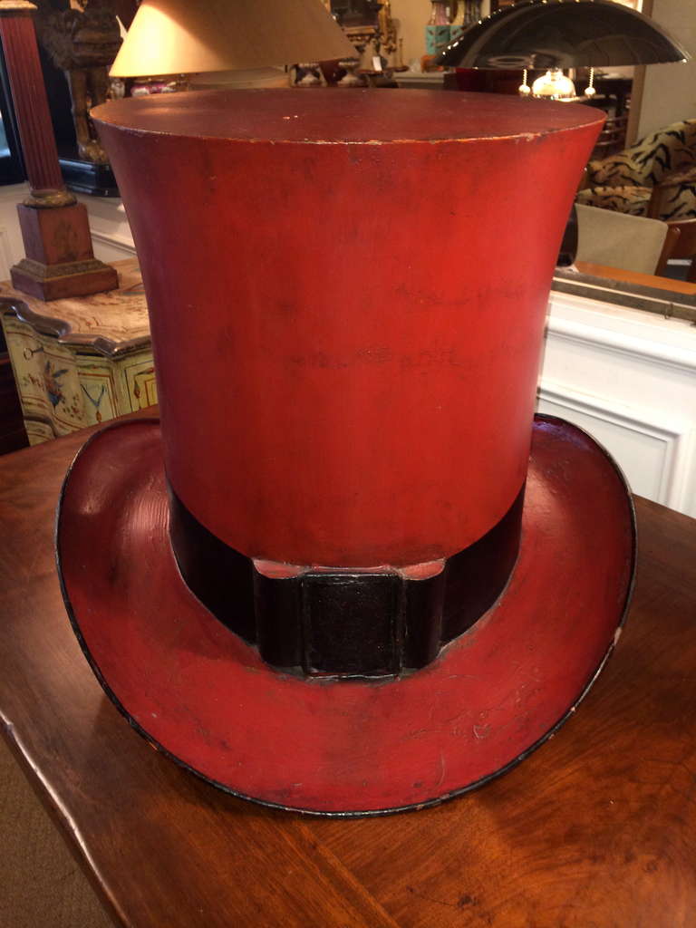 19th century American red painted tin trade sign in the form of a top hat. With black buckle.
