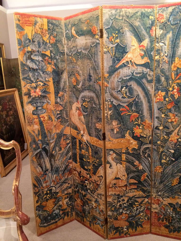Fantastic large-scale 19th century, (or possibly earlier) painted linen six-panel screen depicting a sumptuous garden with an ornate railing, various birds, urns with plants, amidst a background of unruly tropical vegetation. From a distance it is