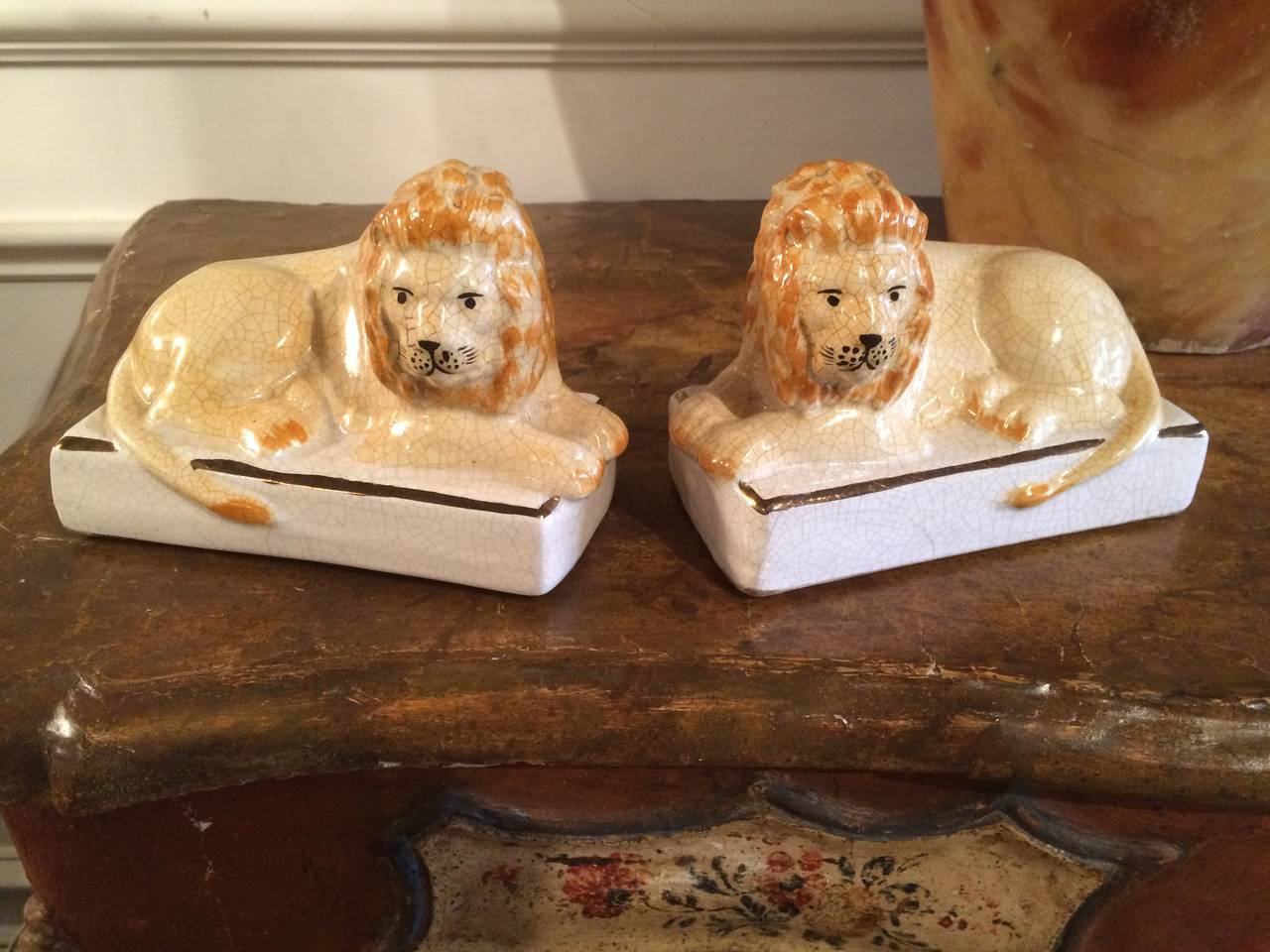 Charming pair of English Staffordshire porcelain lions, beautifully modeled on raised white plinths with gilt borders. Top quality painting, with wonderfully craquelure glaze. These are the best pair available.