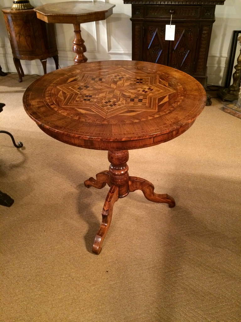 19th century Italian tilt top side or center table with elaborate marquetry top inlaid with walnut and various fruit woods. The tripod base also inlaid with geometric patterns.