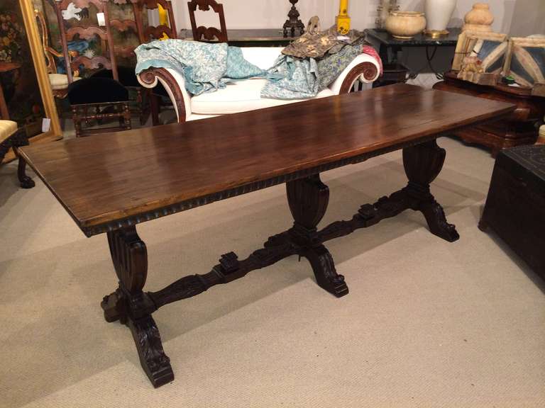 Italian Baroque style walnut refectory table, the top resting on three vase form supports joined by carved stretchers.