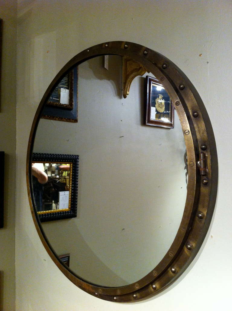 Handsome round Industrial steel frame mirror with a wonderful stressed bronze surface patina. Rivets on the outer ring and flat head screws flush with the surface on the inner.