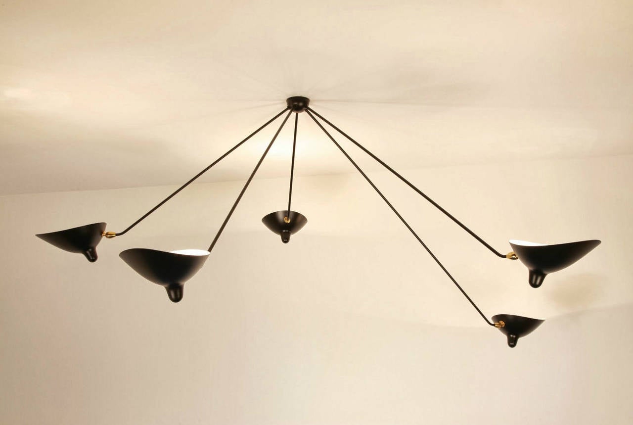 Licensed re-edition produced by the family of Serge Mouille on the site of his original workshop.

This ceiling lamp makes a dramatic addition to a variety of room settings. With five fixed arms of differing lengths and drops and shades that turn