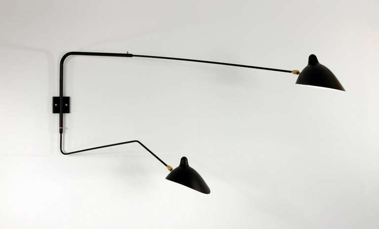 Licensed edition from Serge Mouille's original design, created in 1952.

This sconce is designed so that one short and one long arm rotate at the same time creating a unique effect with illumination. Shades pivot in place. Switches located on