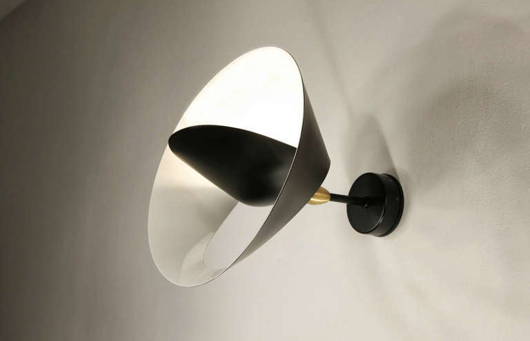 A partial cut allows the outer edge to bend revealing a sculpted ring encircling a central cone reflector to both diffuse and project light into the room. The result is reminiscent of a heavenly body.

The entire collection of licensed Serge Mouille