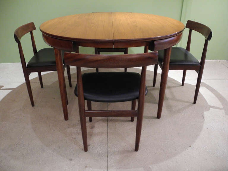 A beautiful and uncommon dining set, recently refinished, with an integrated, folding central leaf which stows beneath the table.