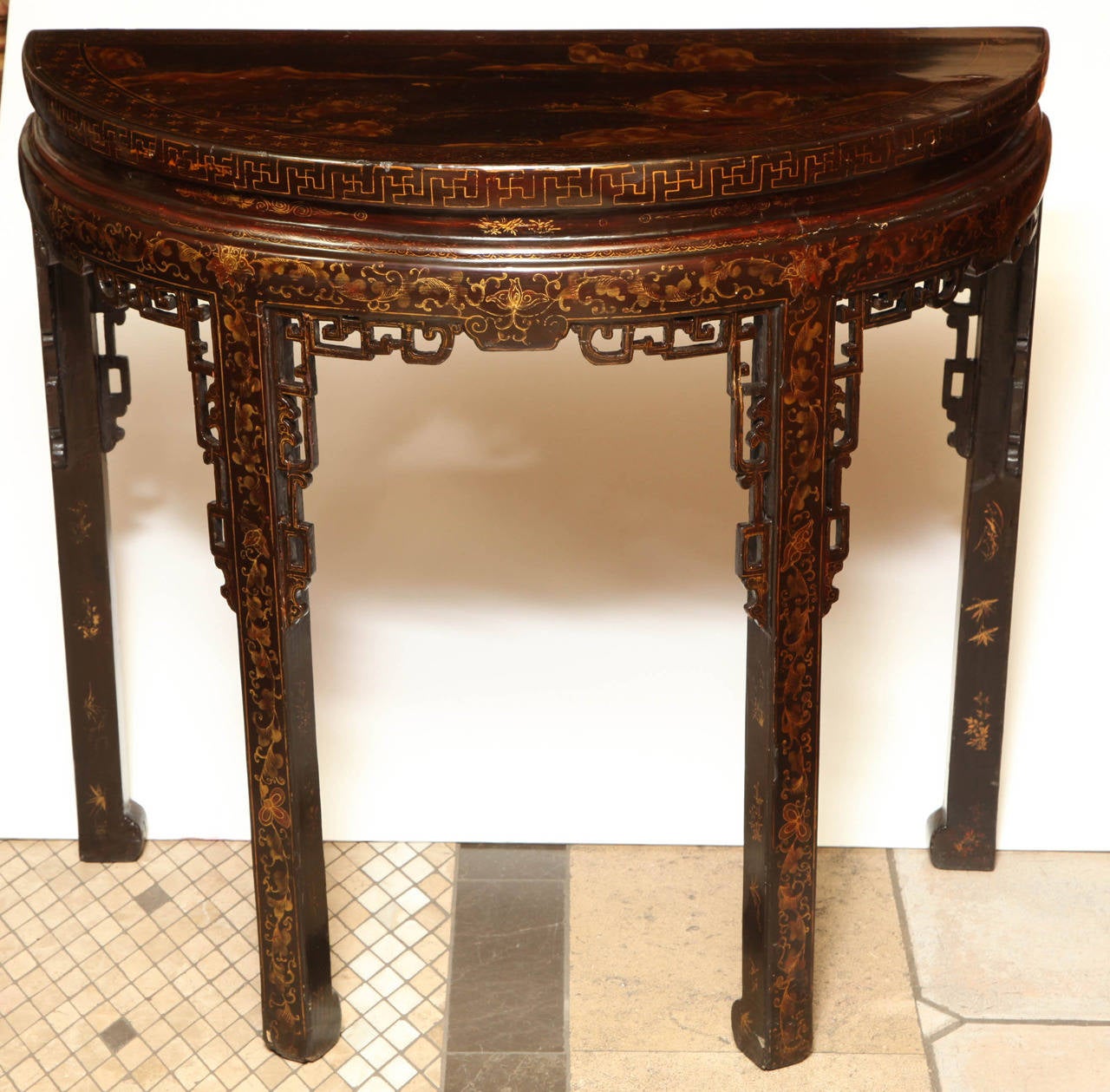 A Fine pair of Chinese export black lacquer and gilt decorated demilune console tables, the tops with landscape scenic decoration, the frieze and legs on all sides with scrolling motifs and with pierced spandrels.