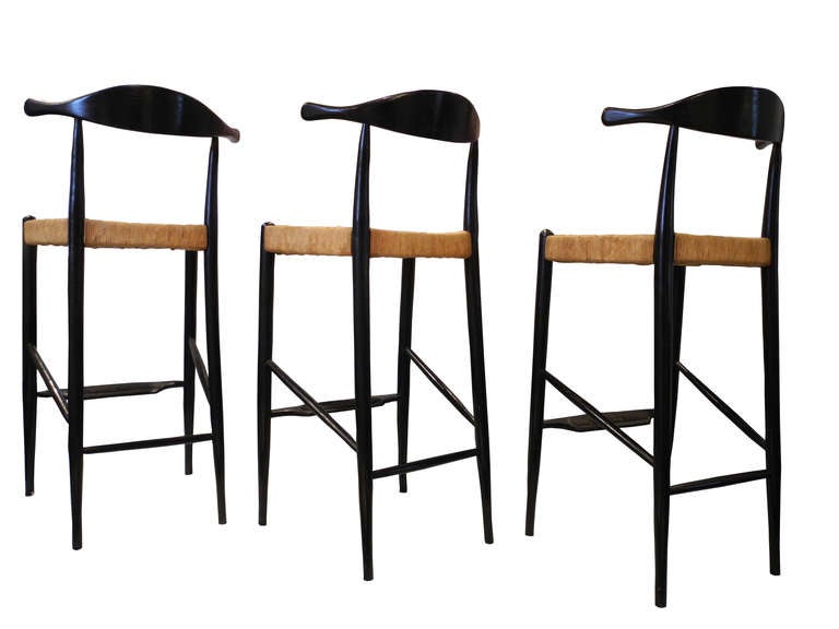 These three matching bar stools are made of rush and black painted wood.
Their backs are uniquely designed in horn like shapes. Designed in the late 1950s. American. The seat height is 27