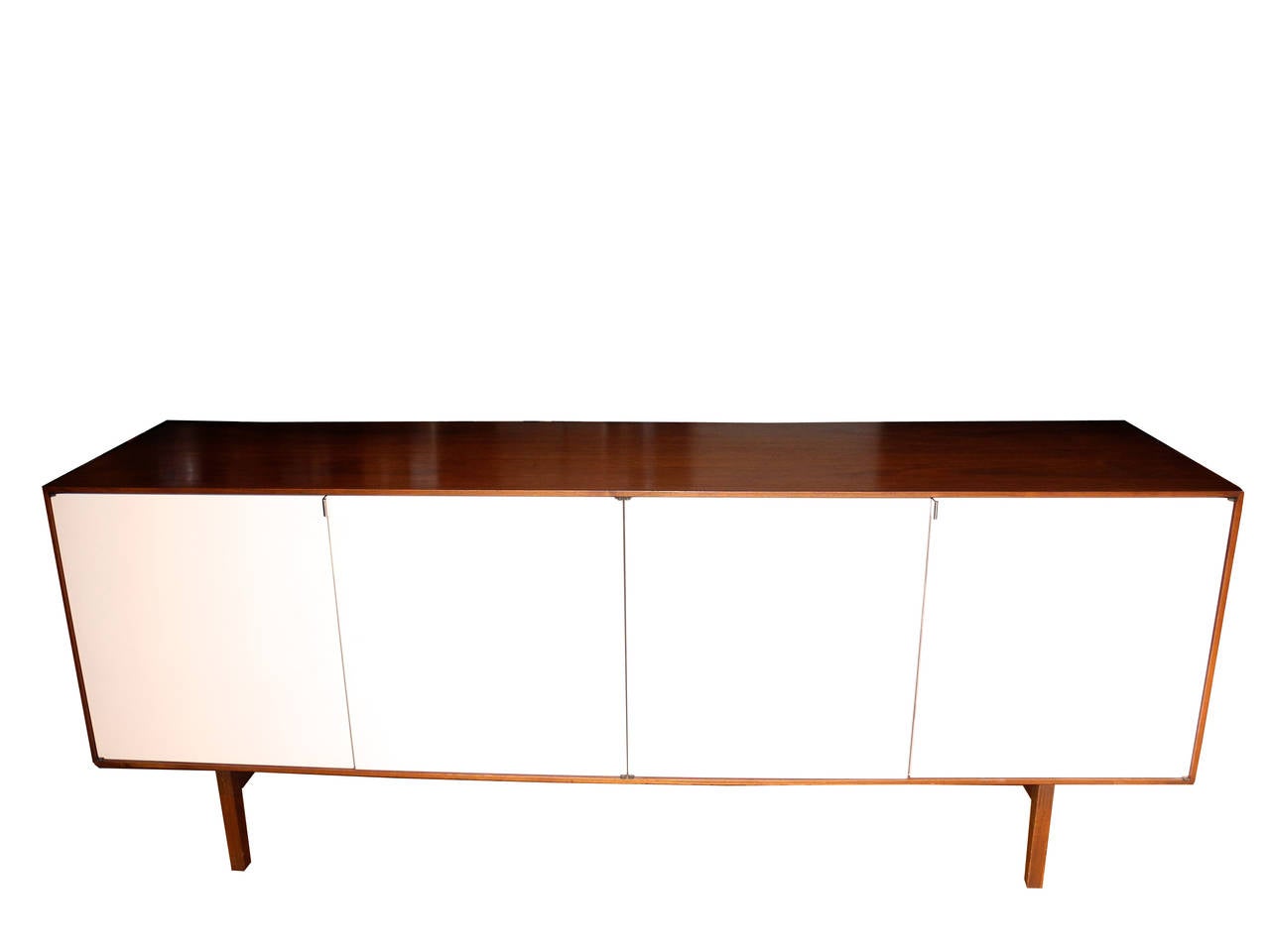 This sideboard with its walnut case and four white lacquered doors is the best of Knoll. Inside in the left cabinet are two long shelves. On the right are drawers and smaller shelves. Great look, great storage.