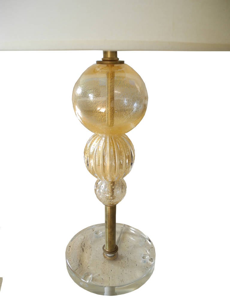 Beautiful blown glass with gold flakes in the traditional Venini style. Shade is 9" x 14" diameter. Base diameter is 7". Height to the top of finial is 24.5" the base is made of Lucite. The shade is off-white fine linen.