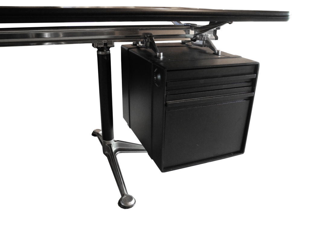 This bold Burdick office desk with an aluminum base was originally designed in 1956 for Herman Miller. The table top has a black finish and the desk boasts a metal hanging file cabinet and a pencil drawer. The half-moon semi-circle edge provides