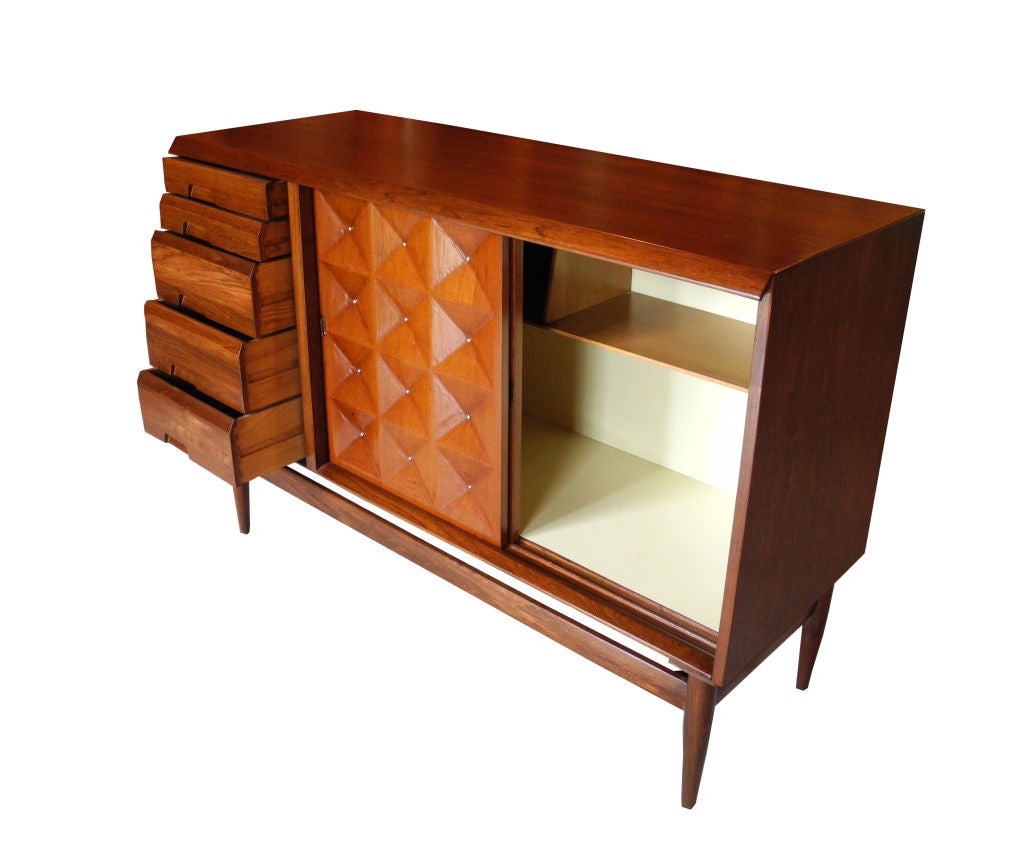 This rare and bold piece in butternut wood features five drawers and a two-sided cabinet for storage. It has a walnut stain with brass studs. This can be used in any room of the home. Great for dining area buffet or living room storage. There is a
