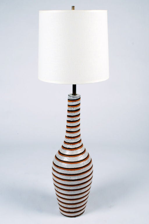 A fun ceramic table lamp with a long, slender neck, narrow urn-shaped body and decorated with orange and black spiral stripe and white-grey ground. By Bitossi. Italian, circa 1960.