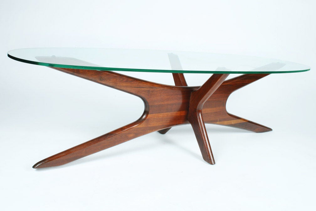A mod cocktail table with an elongated interlocking boomerang form walnut base supporting an oval surfboard glass top, mod. no. 893-TGO. By Adrian Pearsall for Craft Associates. U.S.A., circa 1950. [DUF0118]