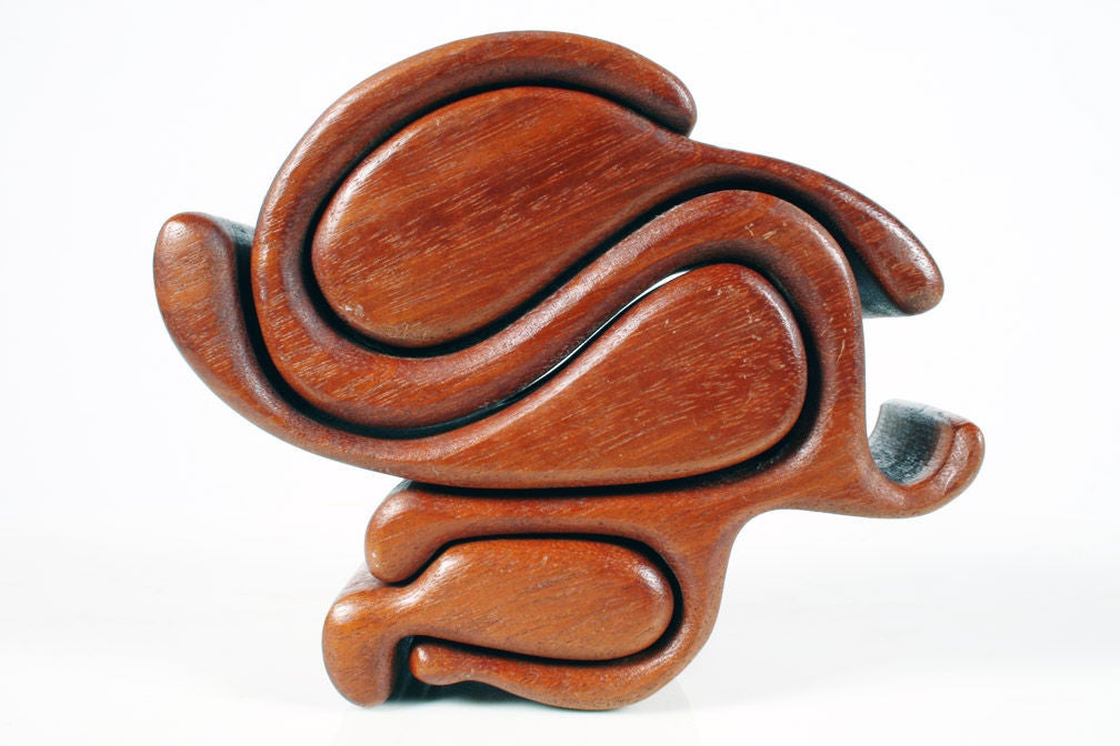 A unique and fun puzzle box in a curly-Q form with three drawers that slide to reveal round interiors, can hold jewelry or other small items.  With artisan's label to the bottom.  American, circa 1970.