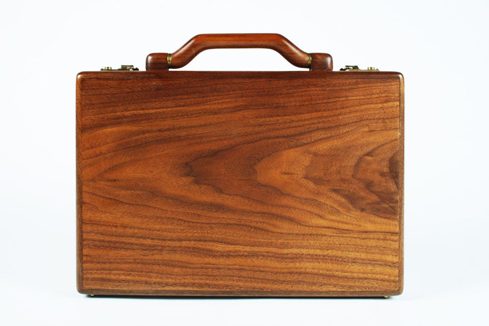 A unique attache case made in solid walnut with brass details.  This handsome briefcase features rounded edges, a wooden swiveling handle, brass fittings and a leather interior with plenty of pockets. Maker's label 
