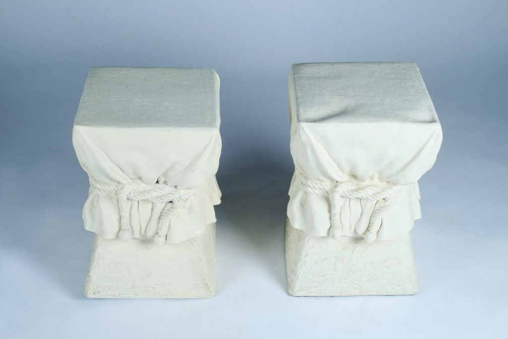 A pair of chic occasional tables each in a square pedestal shape with a cinched rope drapery effect and a faux plaster off-white finish. After Alberto Pinto. U.S.A., circa 1970. [DUF0914]
